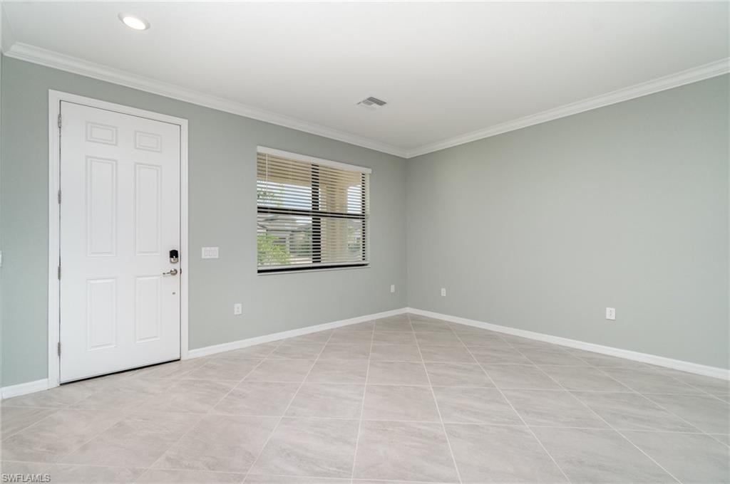 Foyer with crown molding and light tile patterned floors