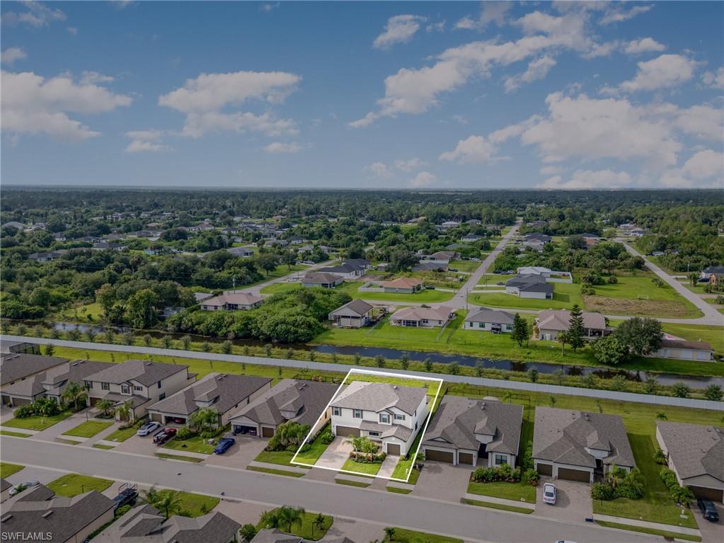 Aerial view of residential area featuring property boundaries highlighted and a nearby body of water