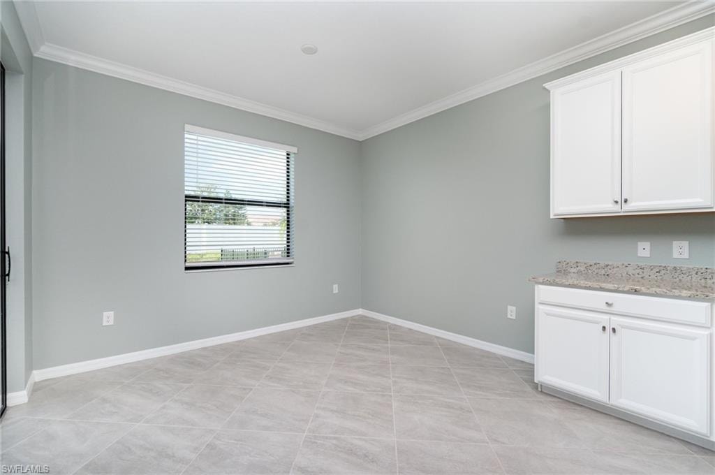 Unfurnished dining area with crown molding and light tile patterned floors