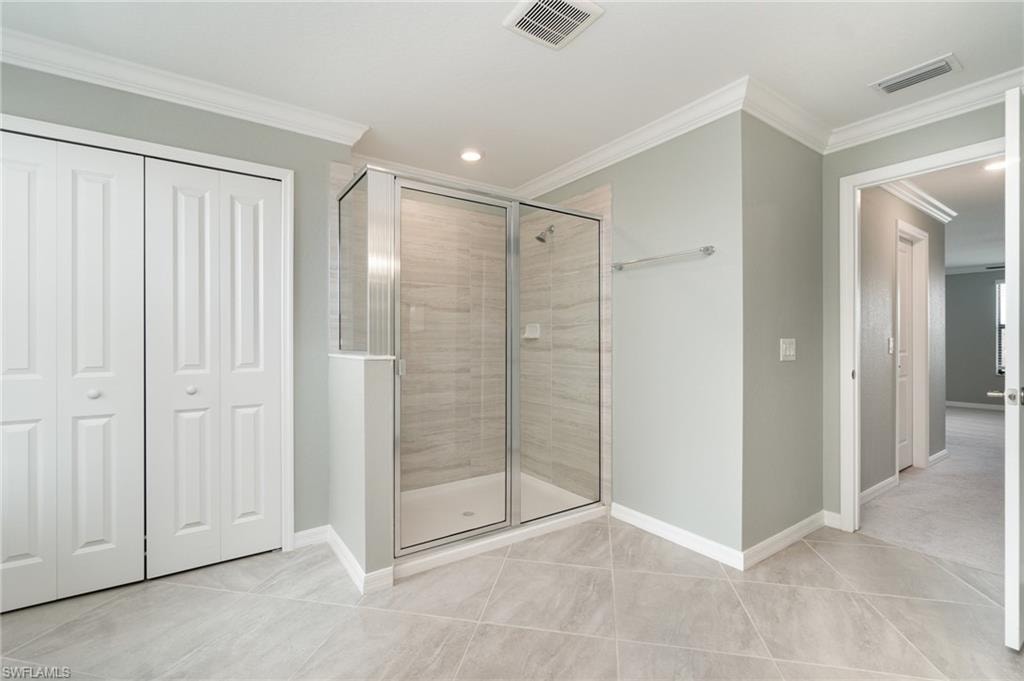 Bathroom featuring a stall shower, a closet, crown molding, recessed lighting, and light tile patterned floors
