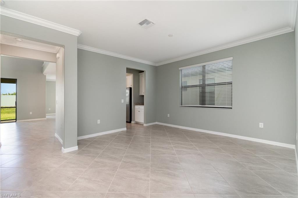 Spare room with ornamental molding and light tile patterned floors