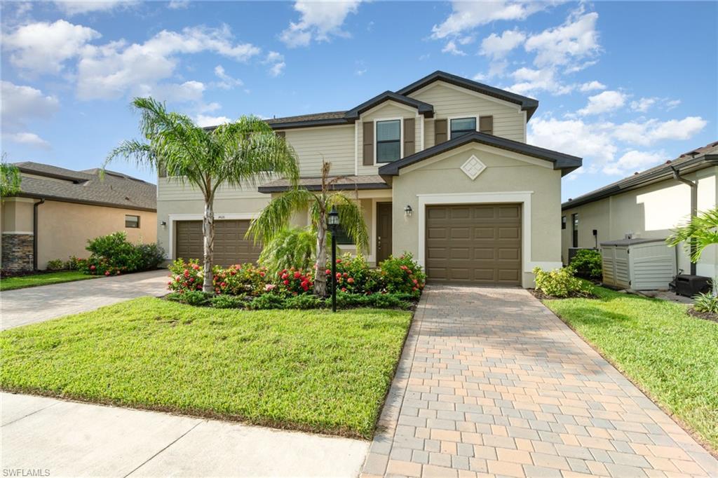 Traditional-style home featuring decorative driveway, stucco siding, a front lawn, and a garage