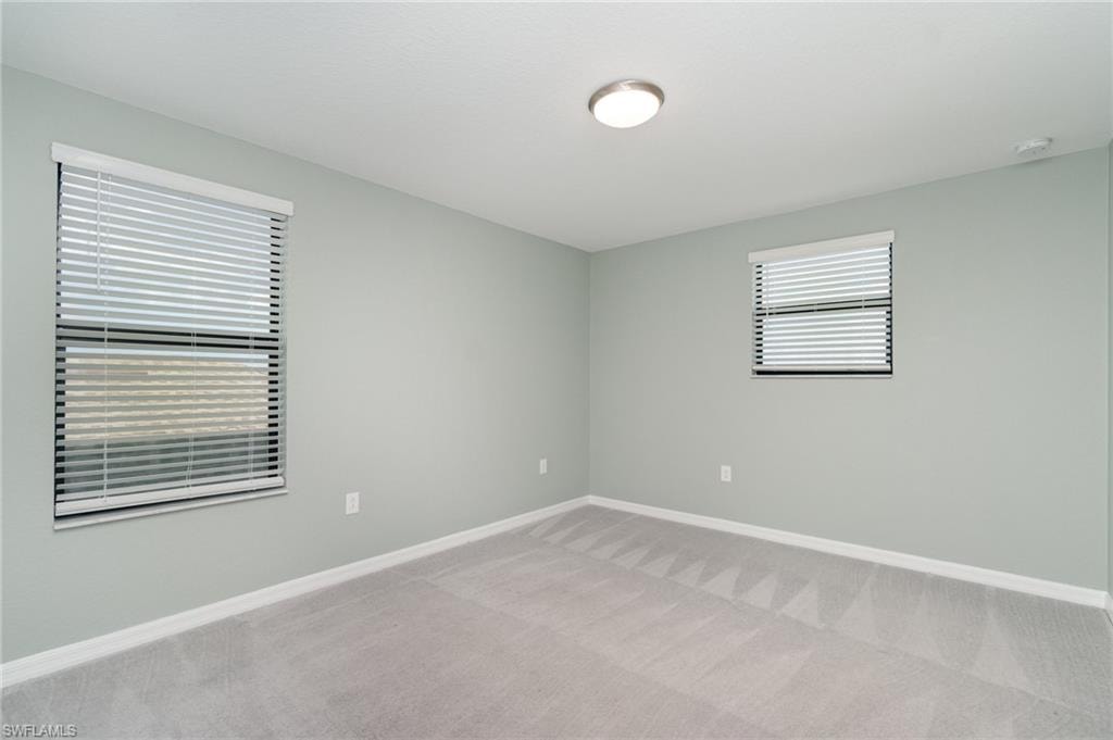 Empty room with light colored carpet and baseboards
