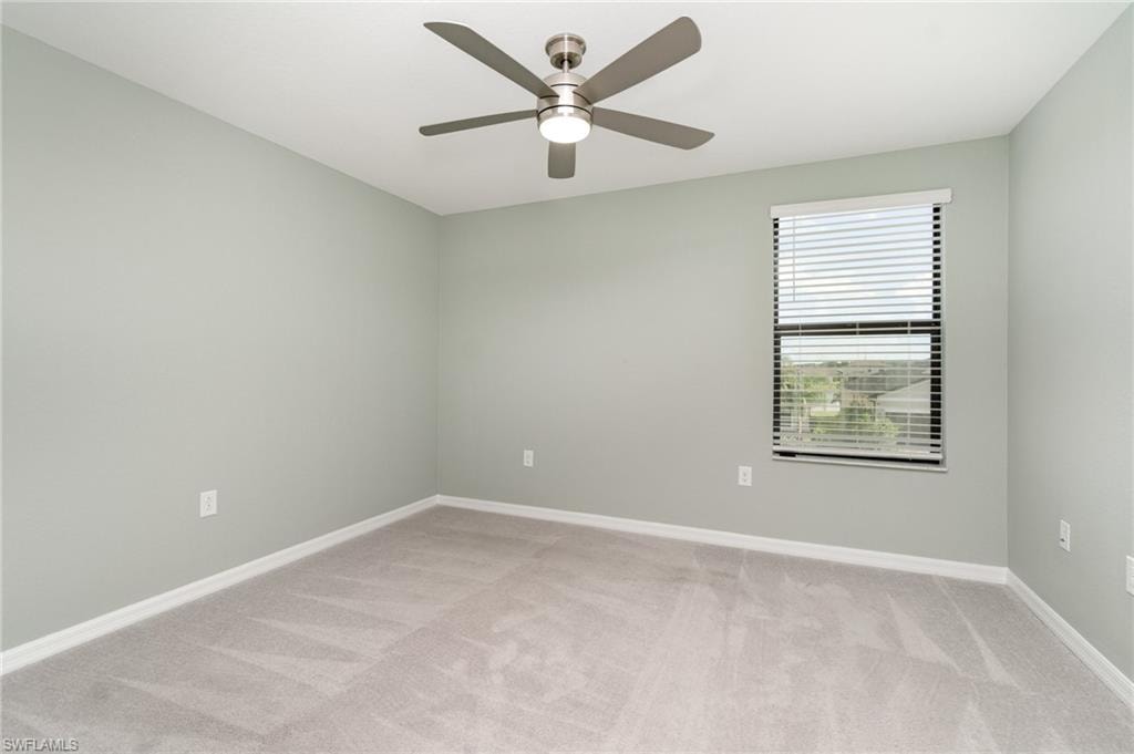 Empty room with light colored carpet and ceiling fan