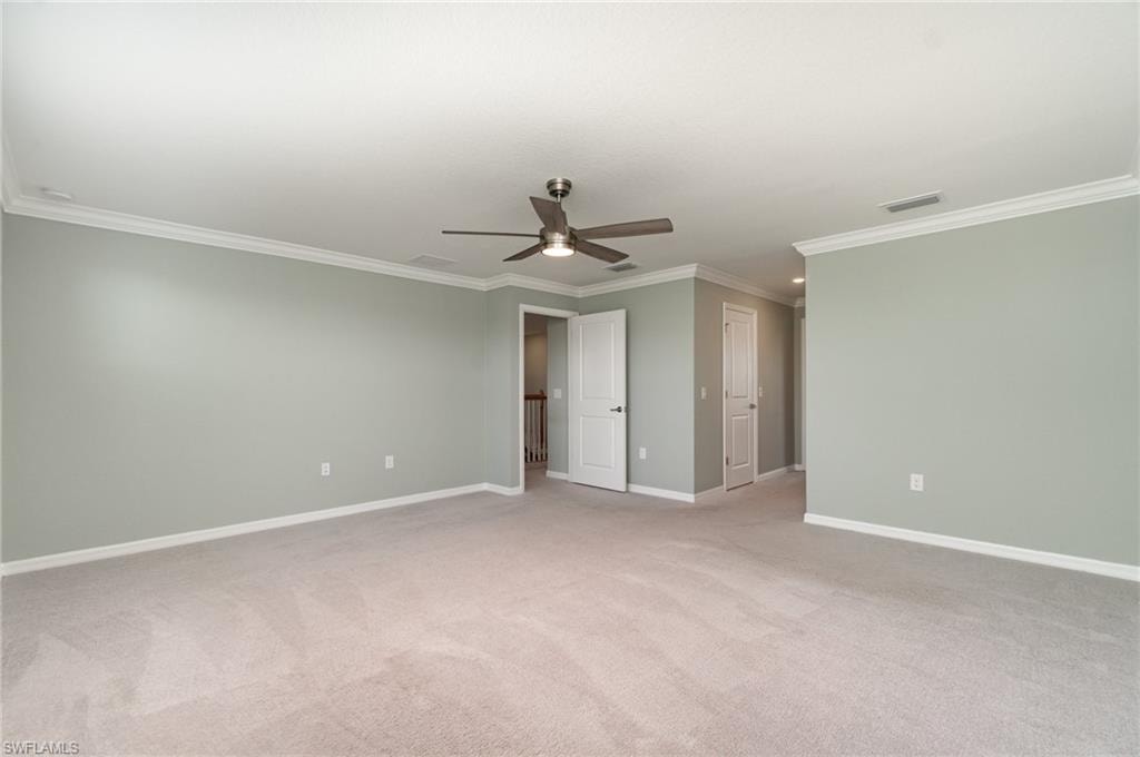 Unfurnished bedroom featuring crown molding, light colored carpet, ceiling fan, and a closet