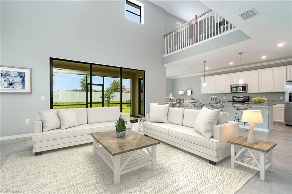 Living room featuring a high ceiling, plenty of natural light, recessed lighting, and ornamental molding
