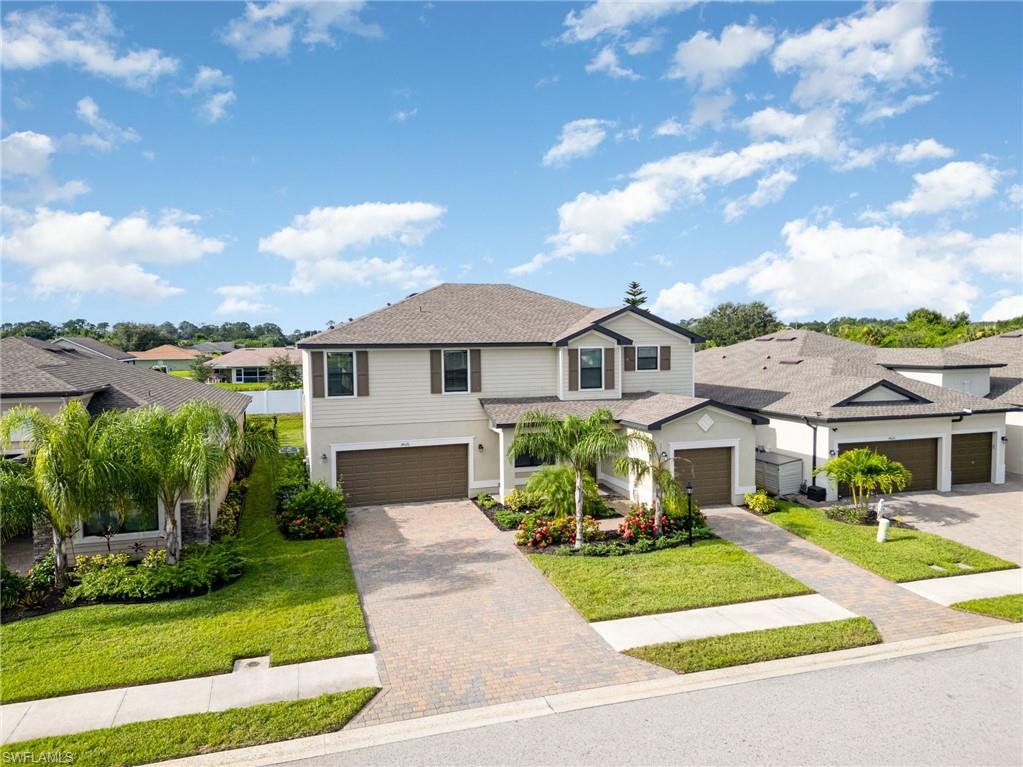 Traditional-style house with a residential view, decorative driveway, an attached garage, and a front yard