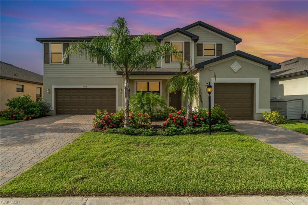 Traditional-style house featuring decorative driveway, a yard, stucco siding, and an attached garage