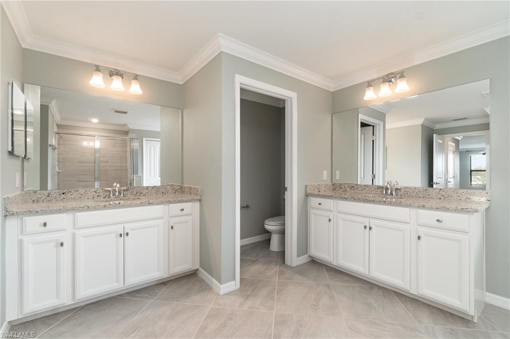 Full bathroom with crown molding, a stall shower, two vanities, and light tile patterned floors