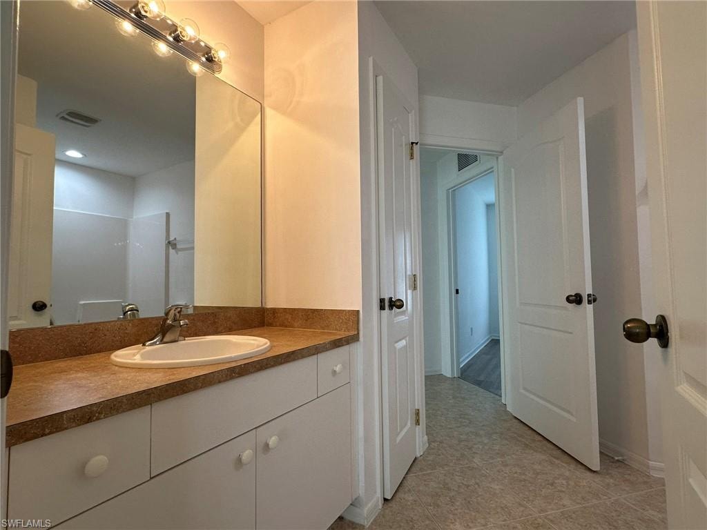 Bathroom with vanity, light tile patterned floors, and a shower