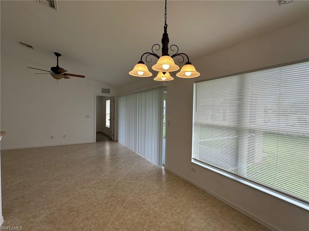 Empty room featuring lofted ceiling, a ceiling fan, and light tile patterned floors