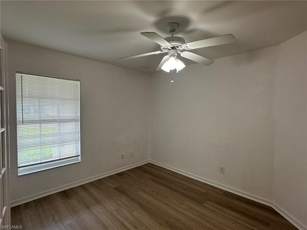 Empty room featuring dark wood-type flooring and a ceiling fan