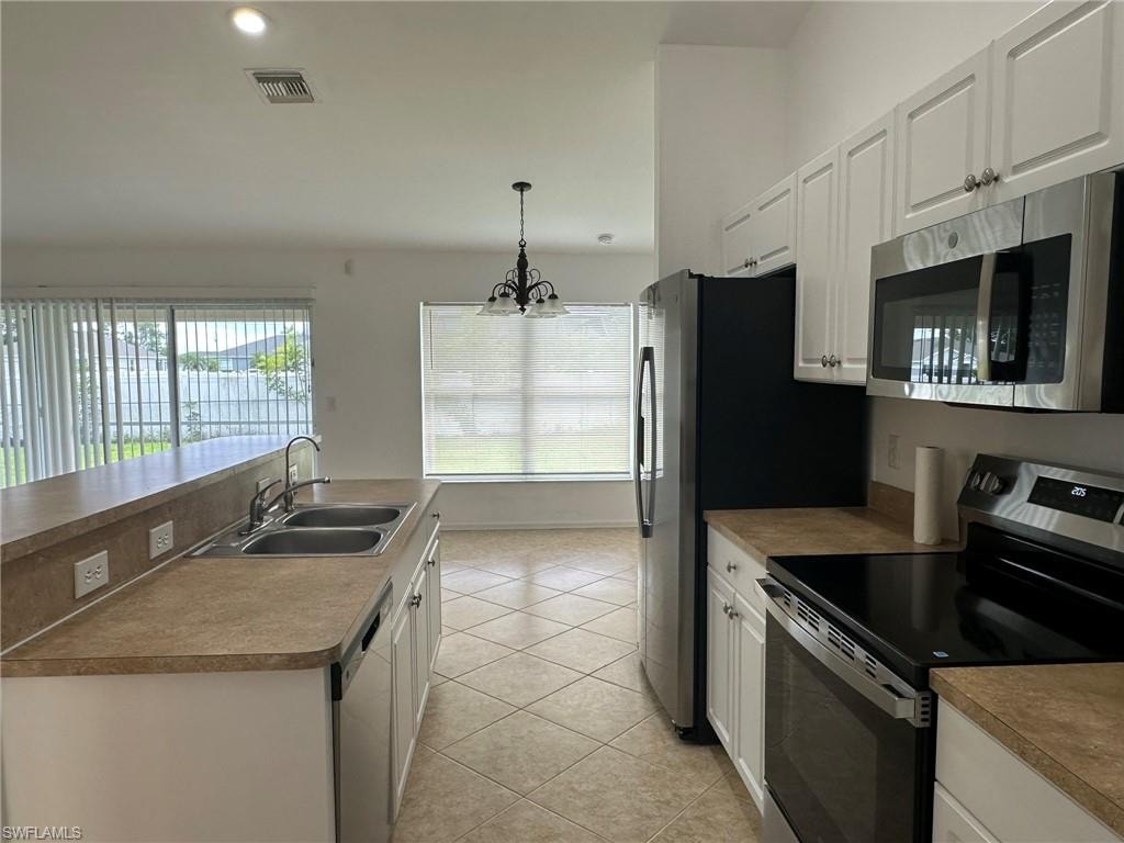Kitchen featuring stainless steel appliances, white cabinets, decorative light fixtures, light tile patterned flooring, and recessed lighting