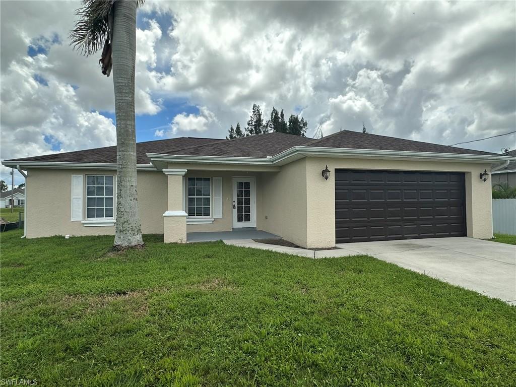 Ranch-style home featuring stucco siding, a garage, driveway, and a front yard