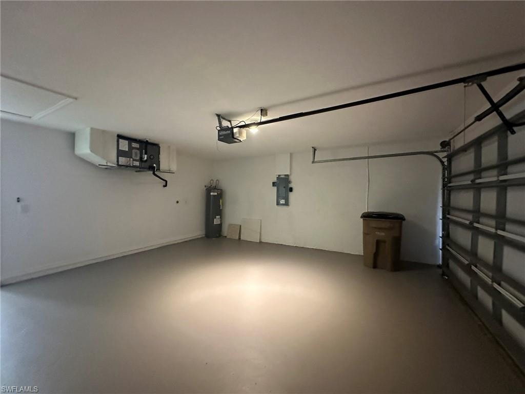 Garage featuring electric water heater, electric panel, and a garage door opener