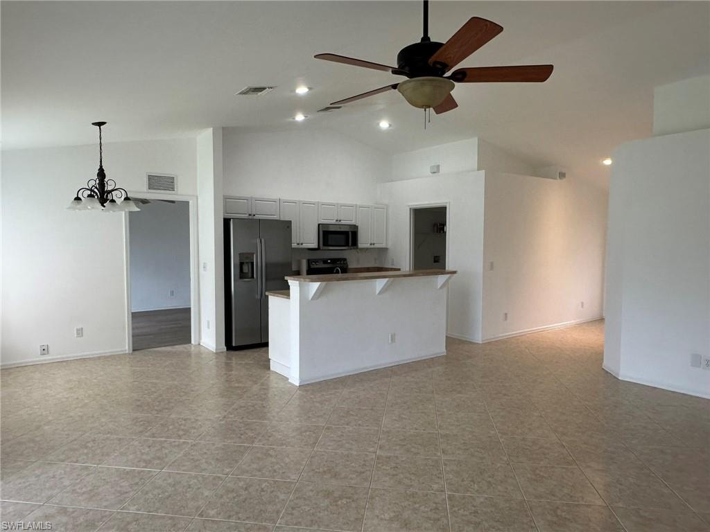 Kitchen with open floor plan, stainless steel appliances, a kitchen breakfast bar, high vaulted ceiling, and a chandelier