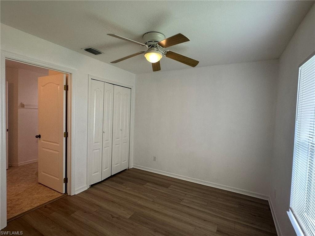 Unfurnished bedroom featuring dark wood-type flooring, a ceiling fan, and a closet