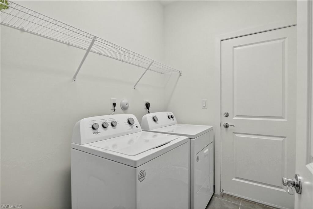 Washroom with tile patterned flooring and washer and dryer