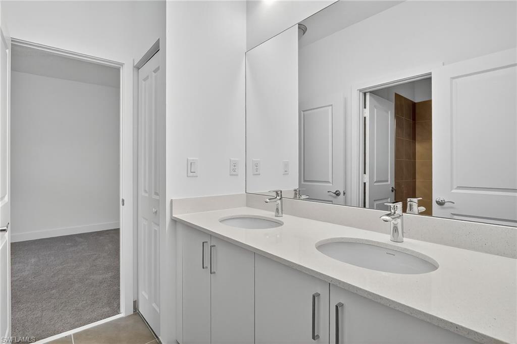 Full bathroom with double vanity and light tile patterned floors
