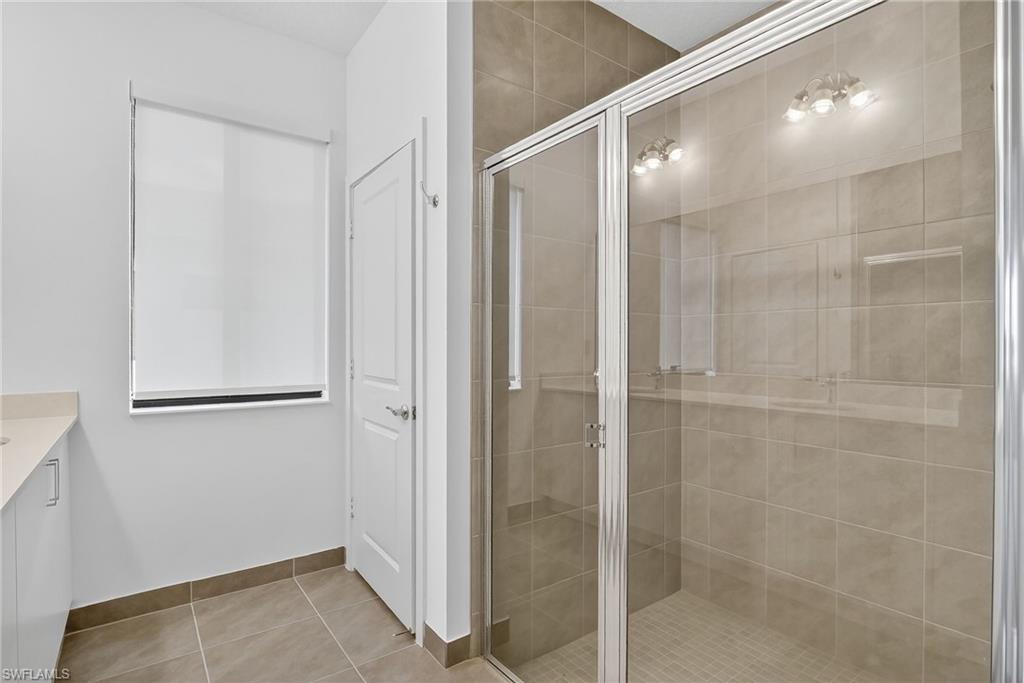 Bathroom featuring vanity, a shower stall, and light tile patterned floors