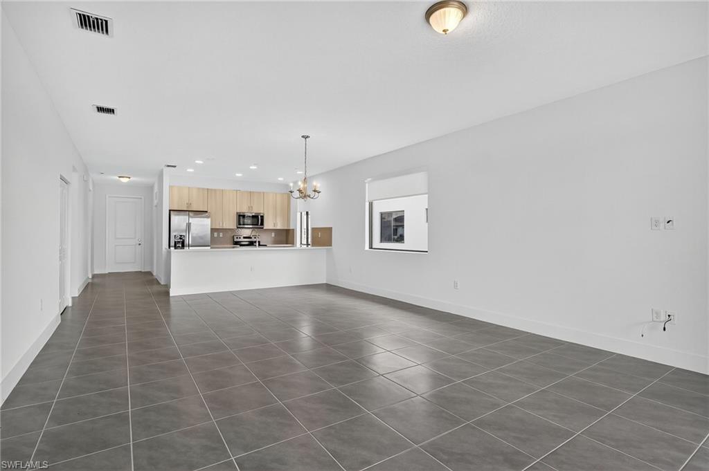 Unfurnished living room with dark tile patterned floors, a chandelier, and recessed lighting