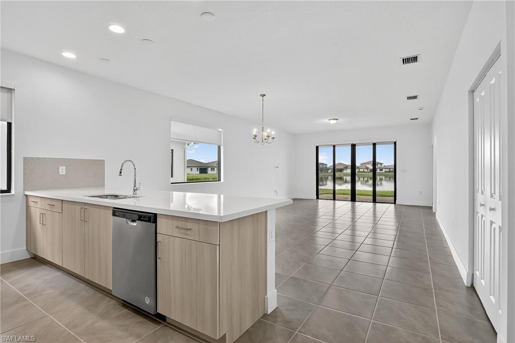 Kitchen featuring light brown cabinetry, healthy amount of natural light, a peninsula, light tile patterned floors, and recessed lighting
