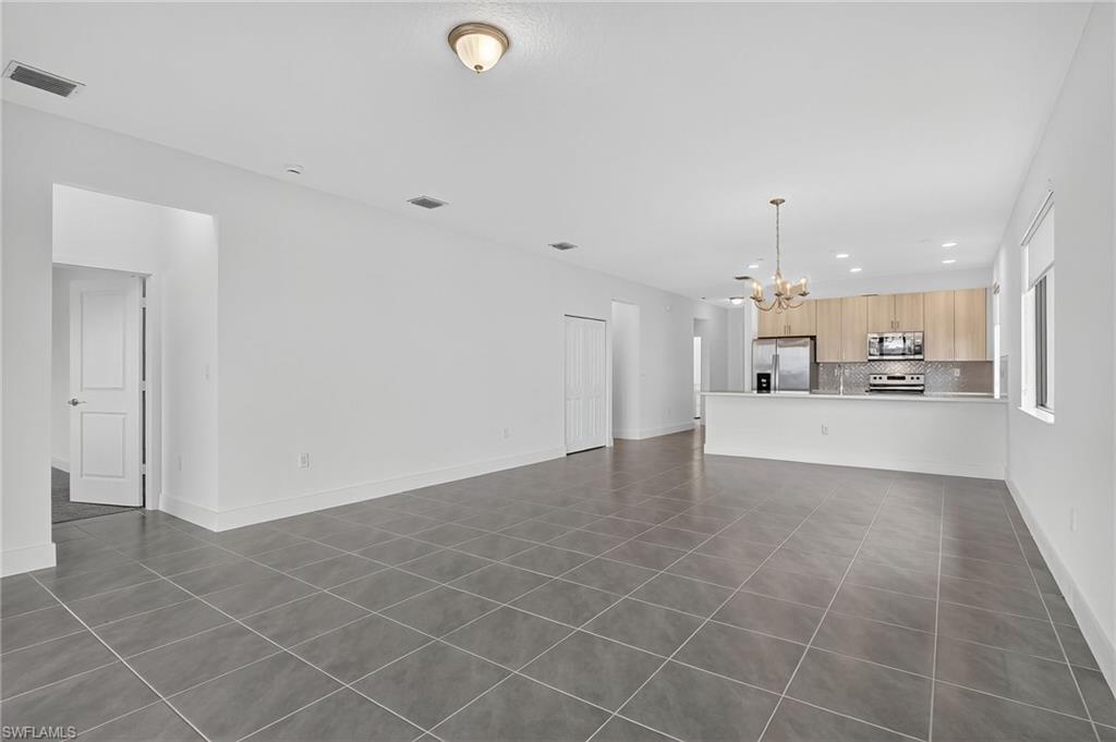 Unfurnished living room with dark tile patterned floors, recessed lighting, and a chandelier