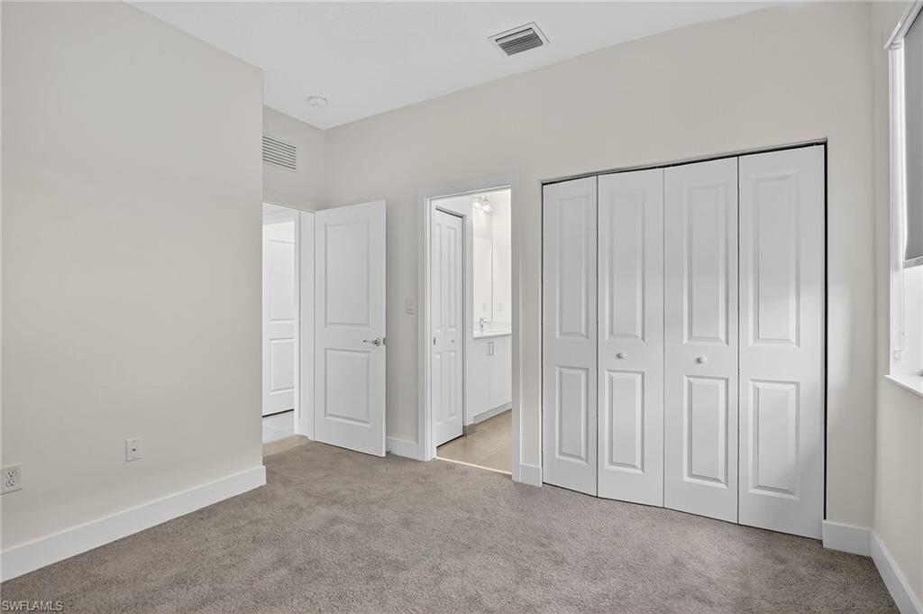 Unfurnished bedroom featuring light carpet, a closet, and connected bathroom