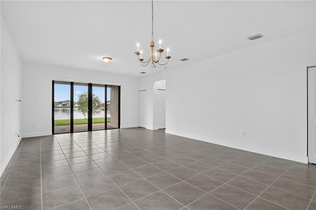 Tiled empty room featuring a water view and a chandelier