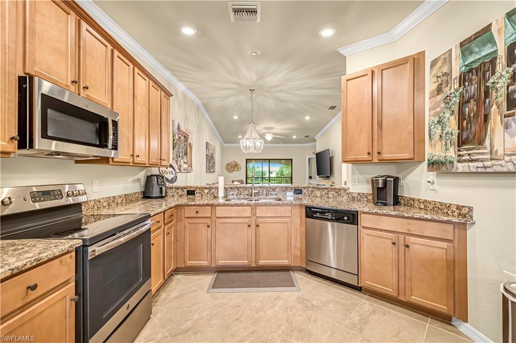 Kitchen featuring stainless steel appliances, crown molding, recessed lighting, pendant lighting, and light stone countertops