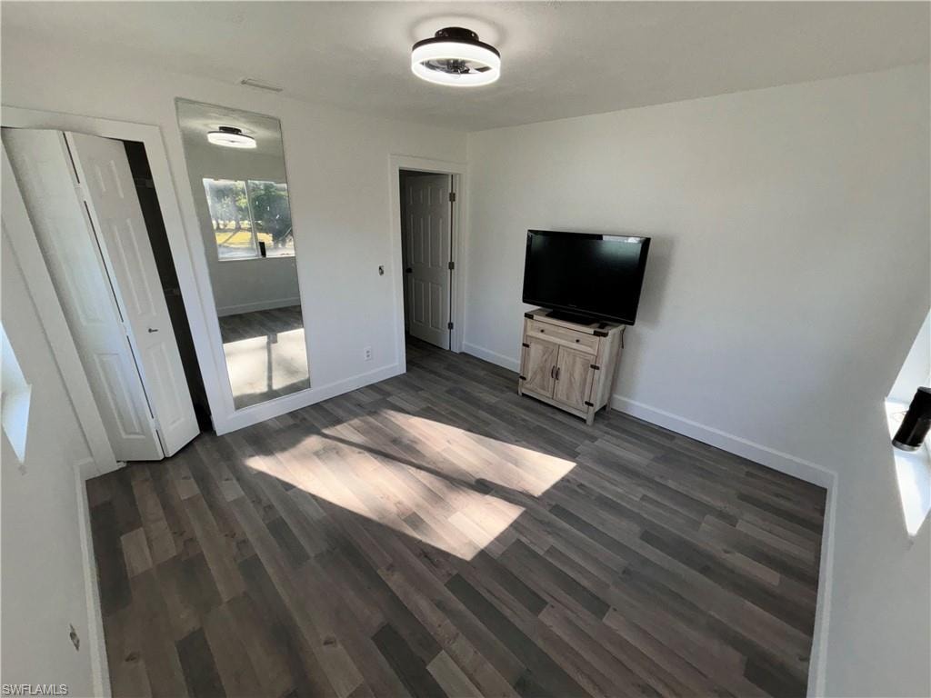 Unfurnished bedroom with dark wood-style floors and a closet