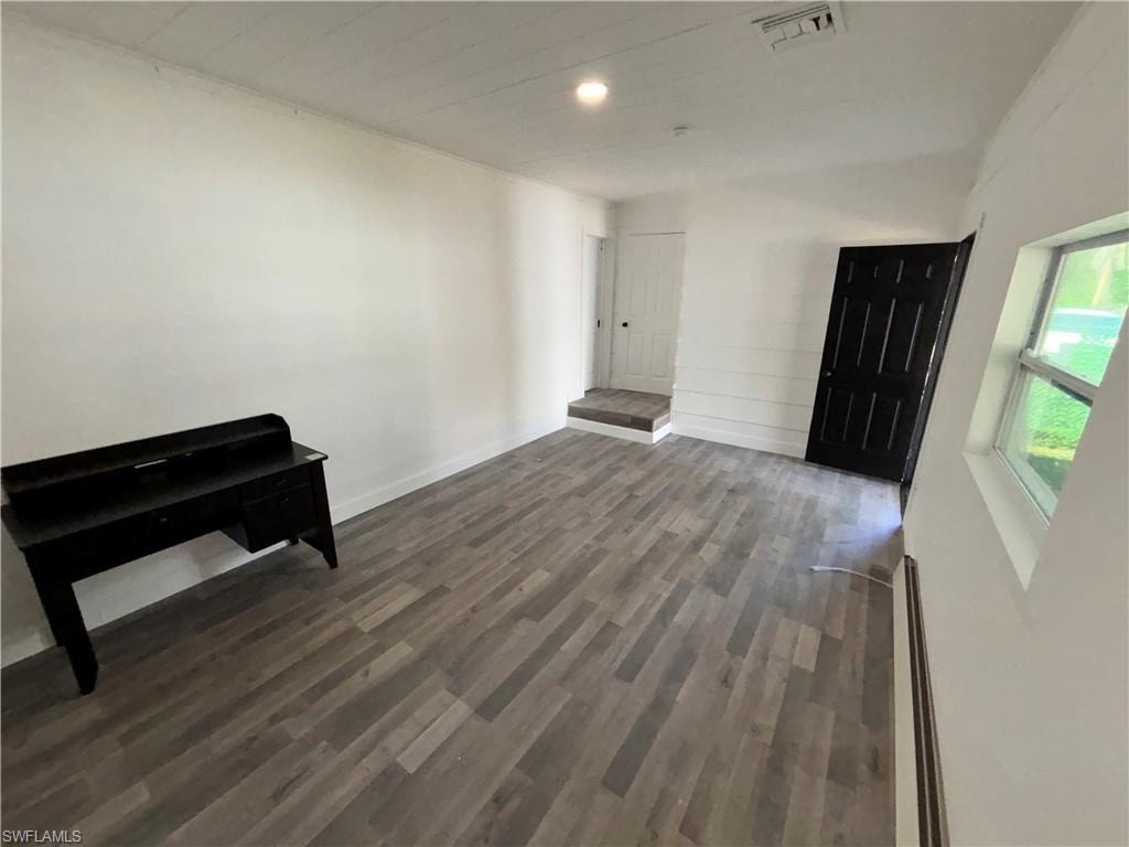 Unfurnished living room with dark wood-style flooring and a baseboard heating unit