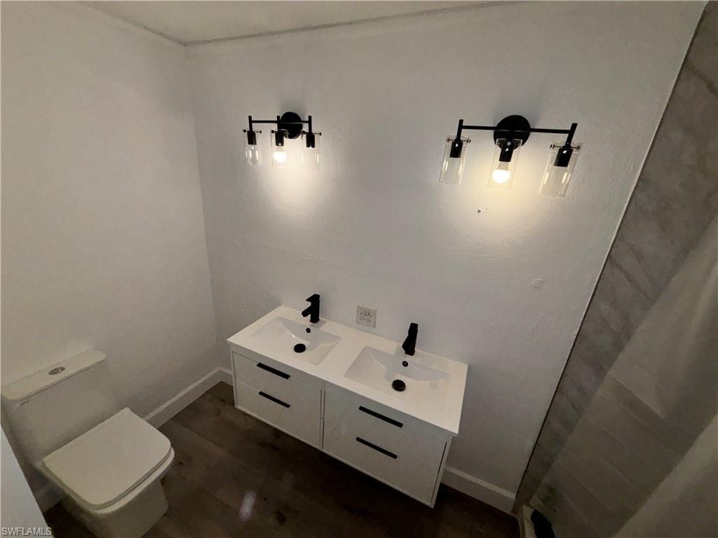 Bathroom featuring double vanity and dark wood-style floors