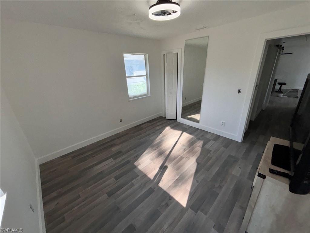 Unfurnished bedroom with dark wood finished floors and a closet
