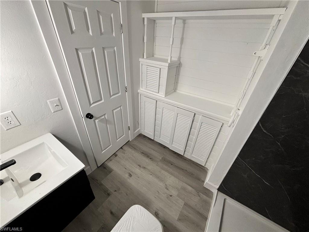 Full bath with vanity and dark wood-type flooring
