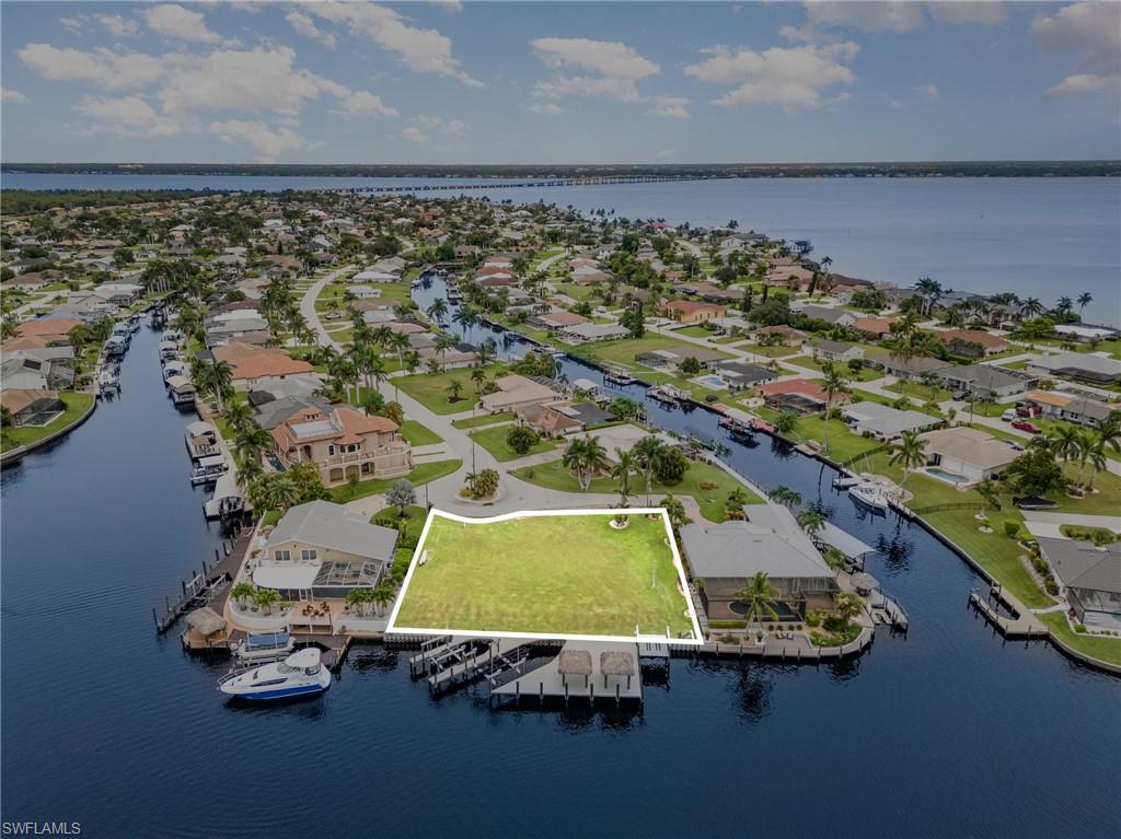 Aerial perspective of suburban area with a large body of water and property boundaries highlighted