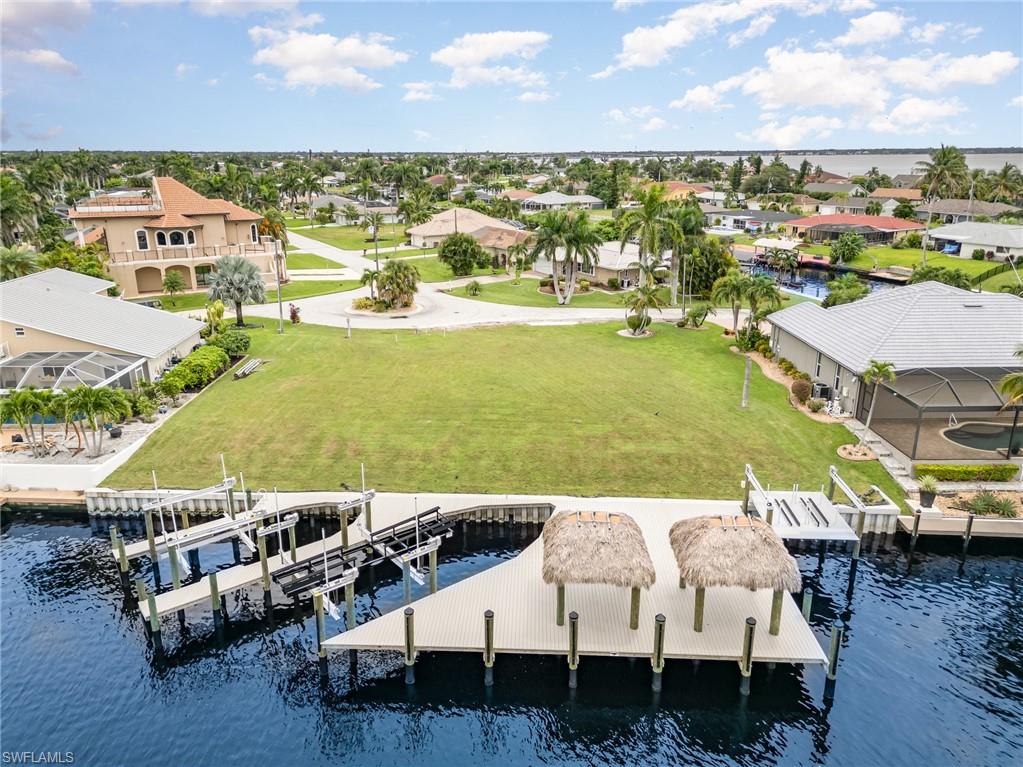 Dock area featuring a water view, a residential view, boat lift, and a lawn