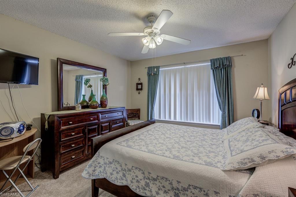 Carpeted bedroom with a textured ceiling and ceiling fan