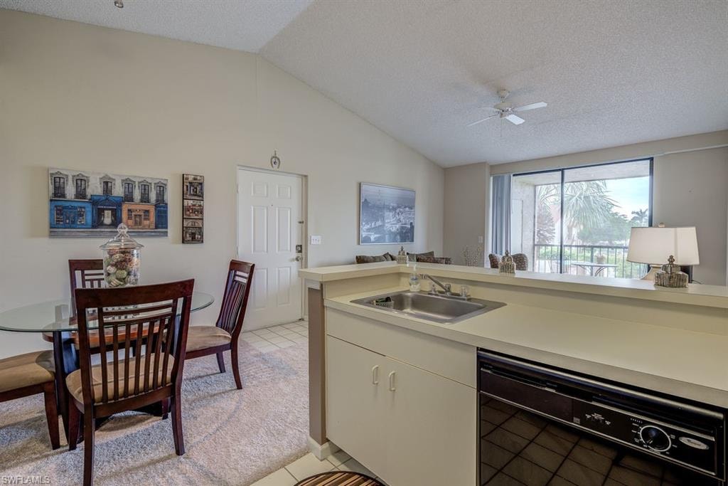 Kitchen with light countertops, dishwasher, light tile patterned floors, lofted ceiling, and a textured ceiling