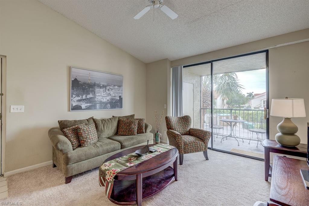 Living area featuring vaulted ceiling, carpet floors, a textured ceiling, and ceiling fan