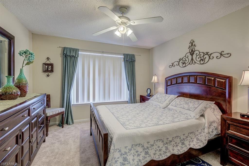 Bedroom featuring light colored carpet, a textured ceiling, and a ceiling fan