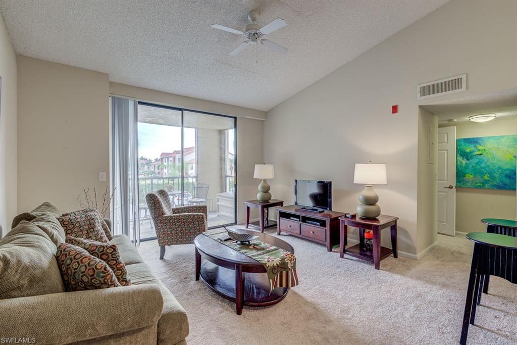 Carpeted living area featuring a textured ceiling, a ceiling fan, and high vaulted ceiling