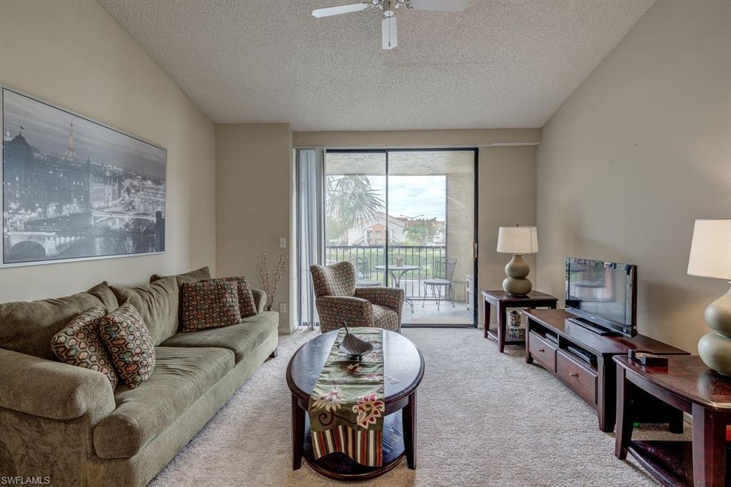 Living room with light colored carpet, a textured ceiling, and a ceiling fan