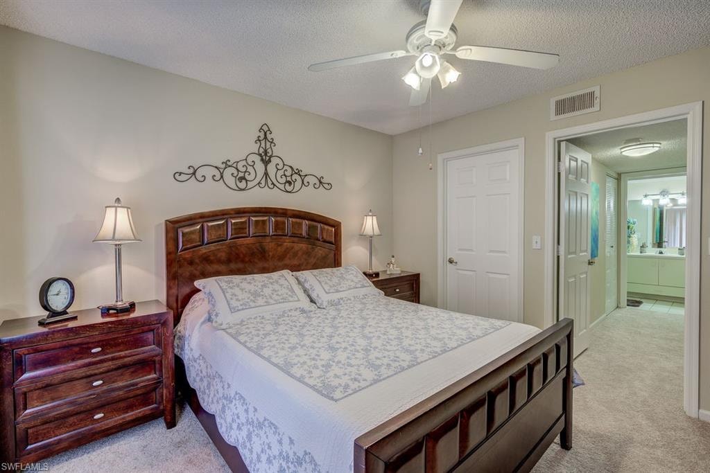 Bedroom with a textured ceiling, light carpet, and a ceiling fan