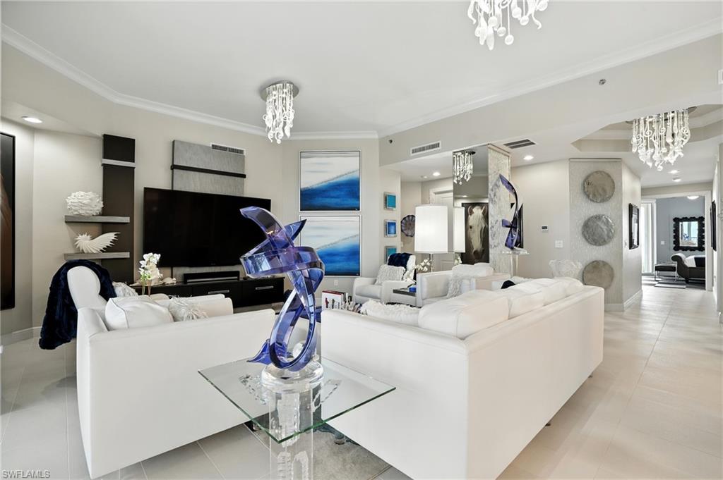 Living area with a chandelier, light tile patterned flooring, crown molding, and recessed lighting - Virtually Edited Image