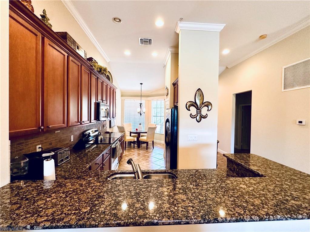 Kitchen featuring stainless steel appliances, kitchen peninsula, and dark stone counters