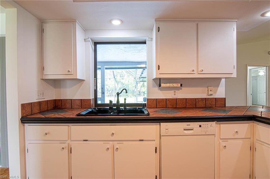 Kitchen features tile countertops, white cabinetry, recessed lighting and a convenient "pass thru" window to the lanai!