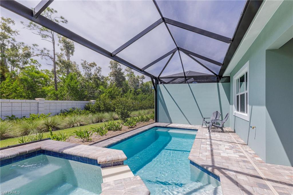 View of pool with glass enclosure, a sunroom, and a patio