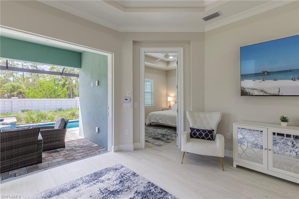 Bedroom with a tray ceiling, light wood finished floors, access to outside, and ornamental molding