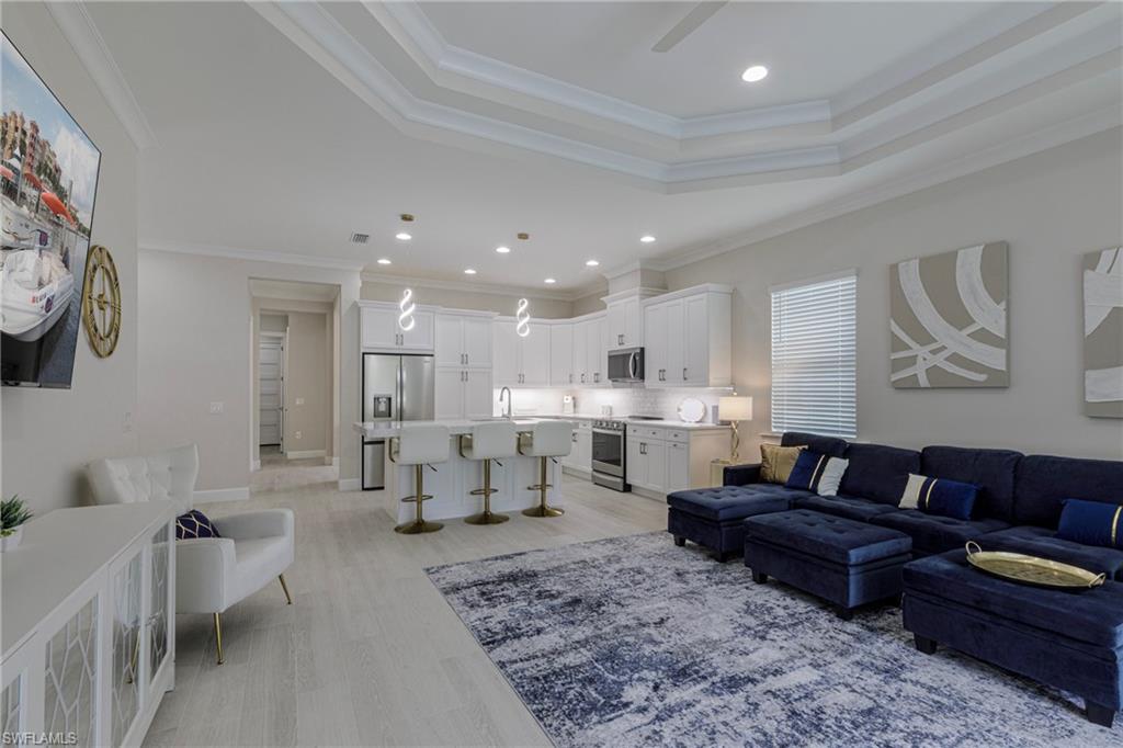 Living room with recessed lighting, crown molding, light wood-style flooring, and a tray ceiling
